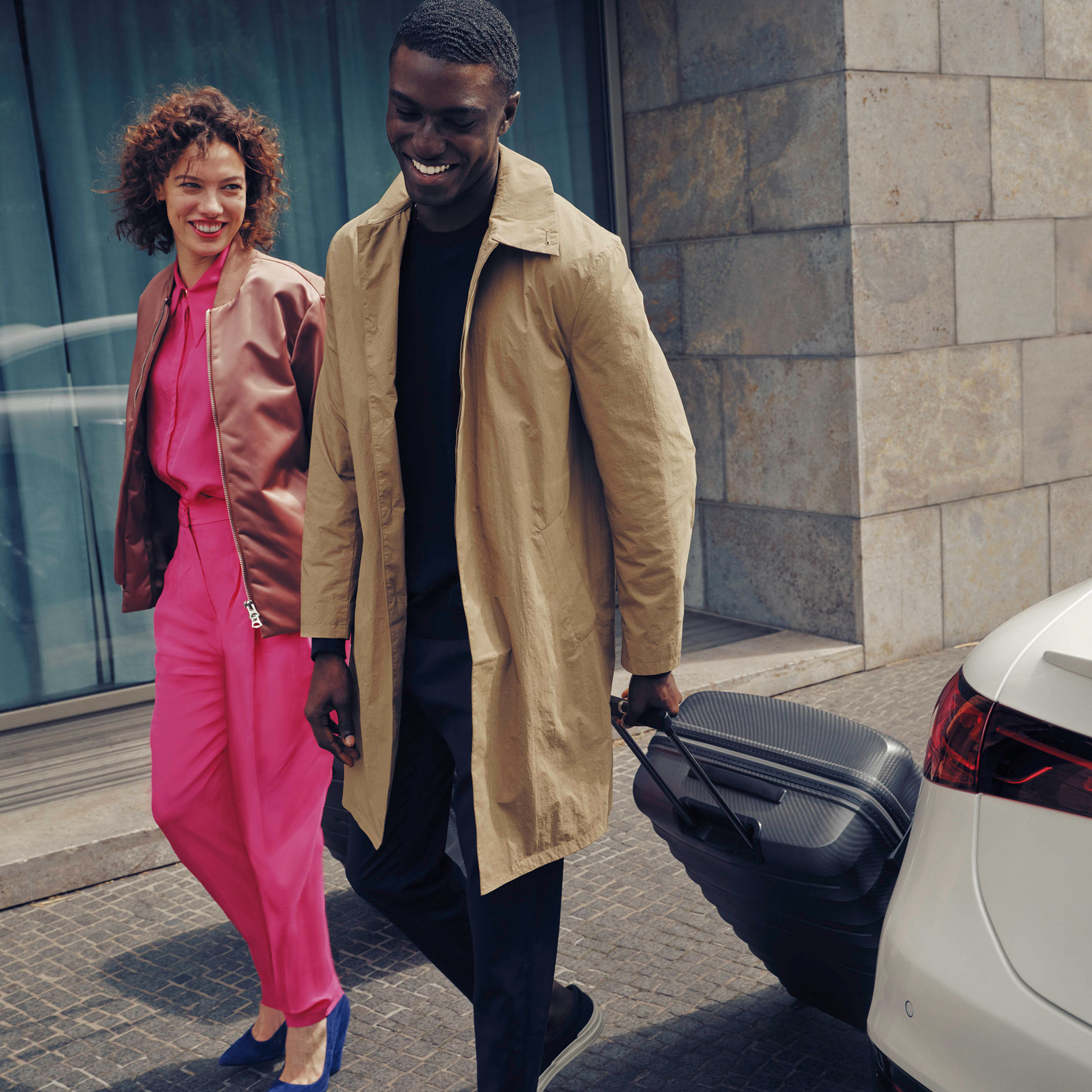 렌트 | 금융 서비스 | 금융 서비스 | 메르세데스-벤츠 Man and woman carrying luggage next to white Mercedes-Benz EQS