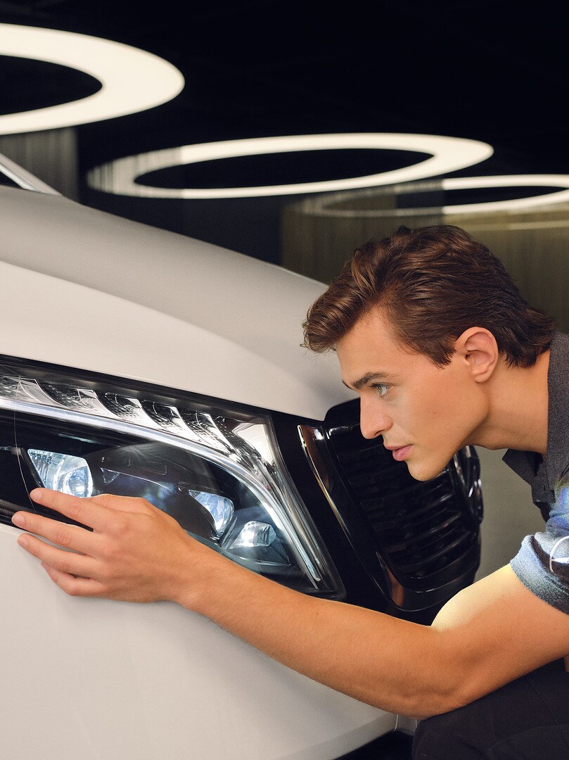 정비 기술자가 메르세데스 차량의 헤드램프를 점검하고 있습니다.