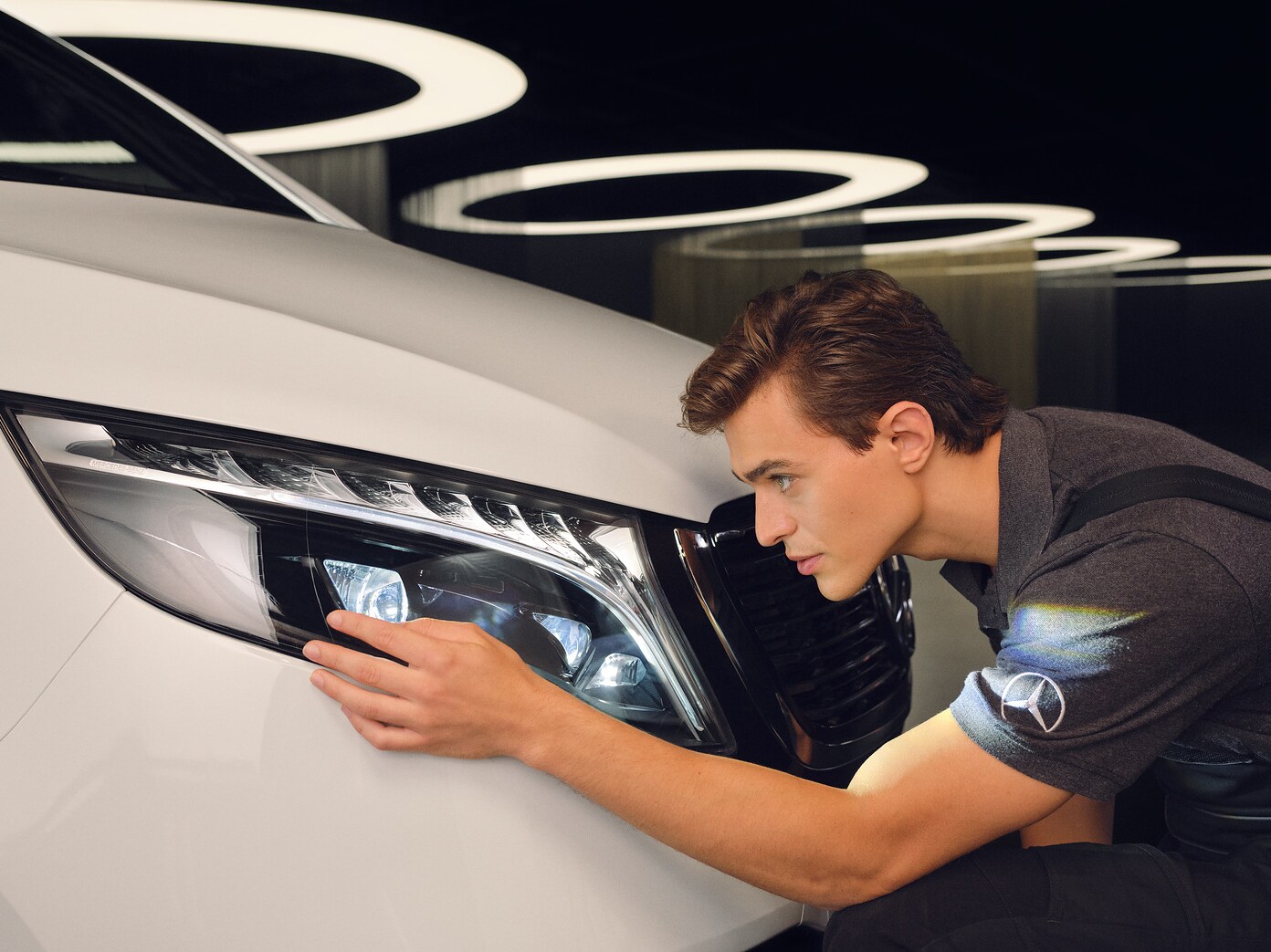 정비 기술자가 메르세데스 차량의 헤드램프를 점검하고 있습니다.