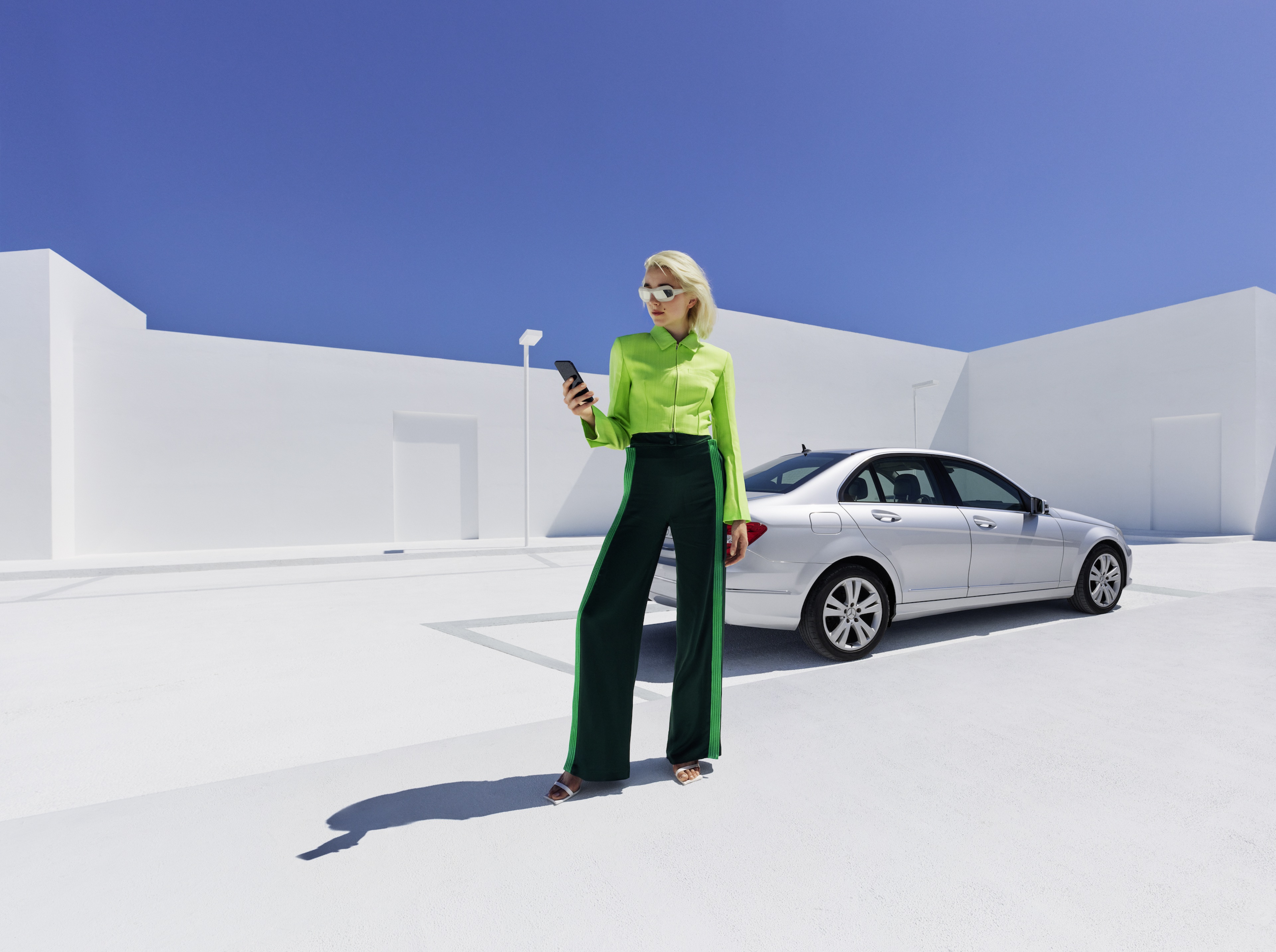 Mercedes-Benz Adapter Mercedes-Benz 차량에 기대어 스마트폰을 보고 있는 한 여성