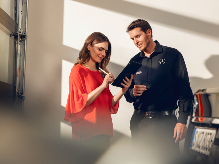 순정 부품 대 모조품 한 여성이 서비스 센터에서 태블릿으로 문서에 서명하고 있습니다.